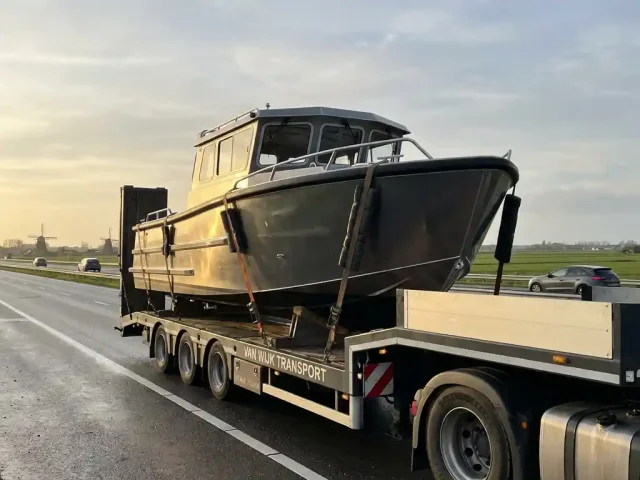 Aluminium tender boot op professionele transporttrailer op Nederlandse snelweg met polders en windmolens op achtergrond