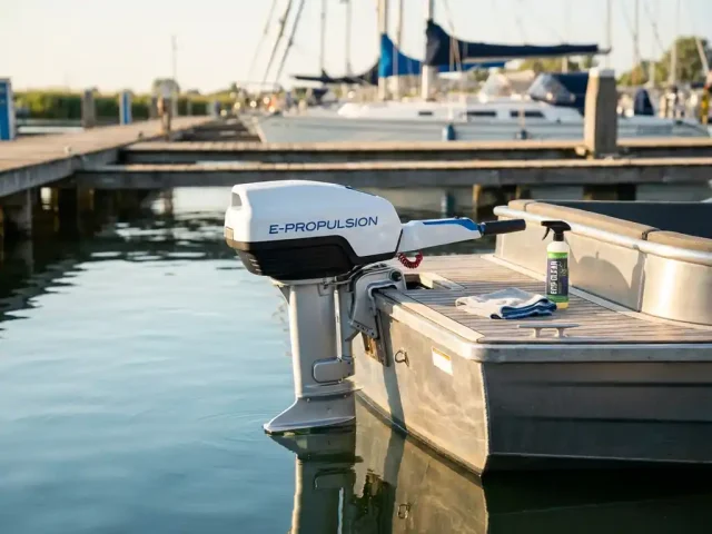 Witte elektrische buitenboordmotor op aluminium sloep met onderhoudsgereedschap op het dek in jachthaven