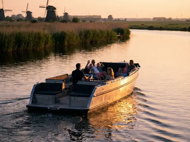 Moderne aluminium zeilboot met families aan boord vaart over kalme Nederlandse wateren tijdens gouden uurtje